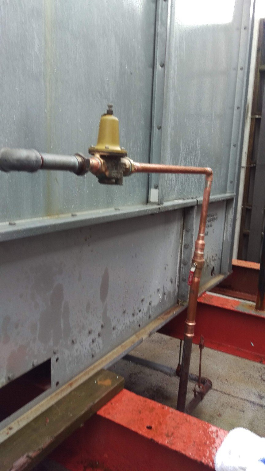 Cooling tower water supply piping with a pressure-regulating valve and manual isolation valve.